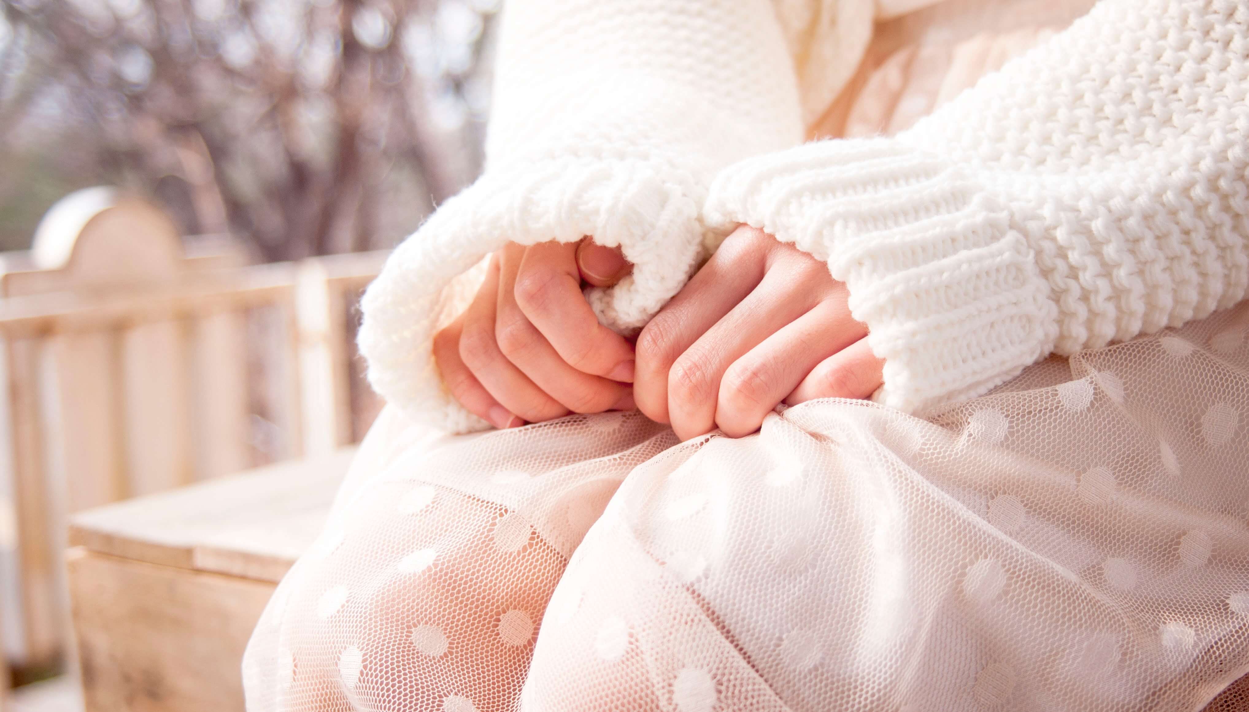 Image of a woman sitting on a chair with hands in her lap