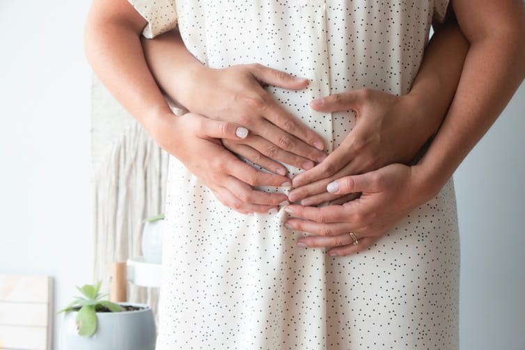 Image d'une femme enceinte tenue dans les bras